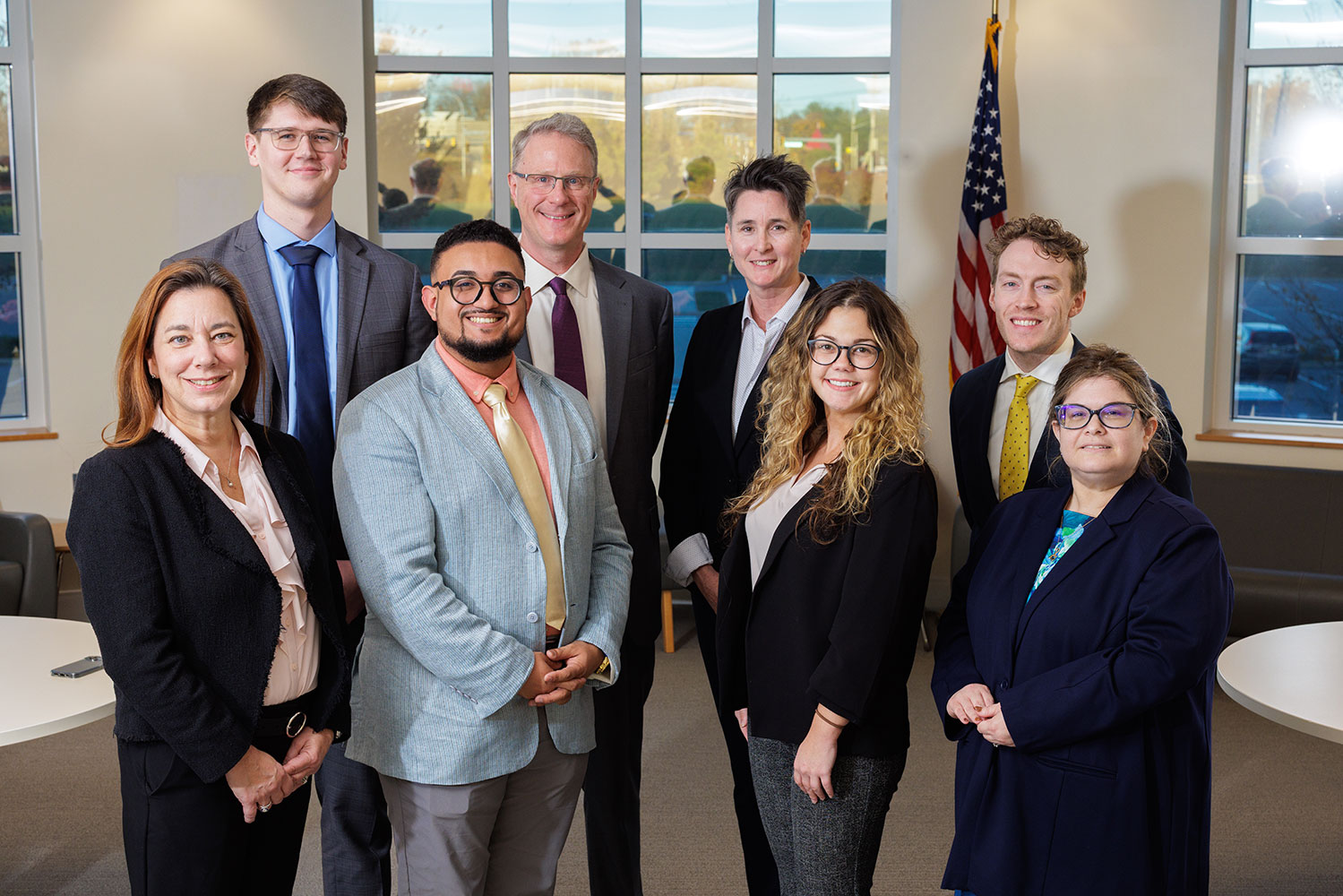 Eight people dressed in suits standing and smiling at the camera