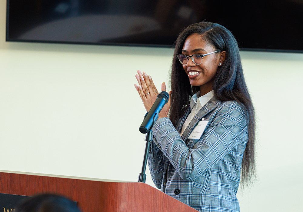 Woman standing at podium clapping and smiling