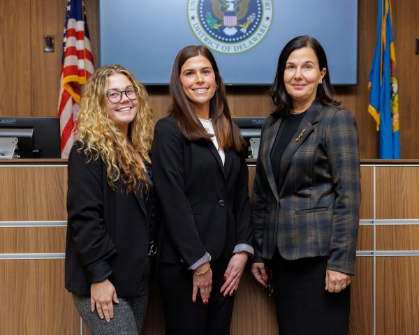students posing in a courtroom in front of a judge's bench